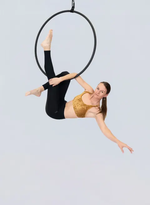Aerial hoop – lektorka visí ve vzdušném kruhu v pozici s jednou nohou nahoře a druhou opřenou o obruč ve studiu Prostě se hýbej, Opava.