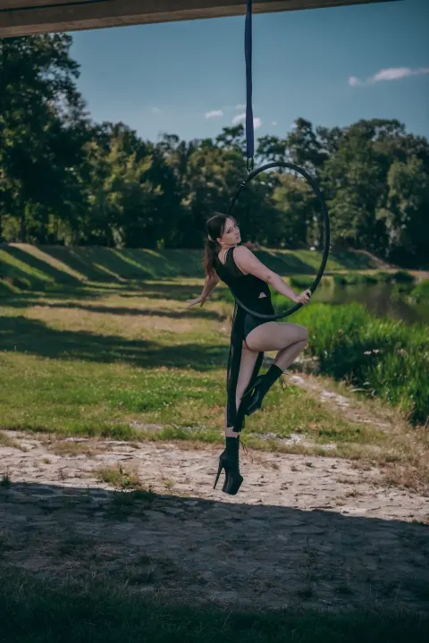 Aerial hoop – lektorka visí na kruhu v elegantní akrobatické pozici ve studiu Prostě se hýbej, Opava.