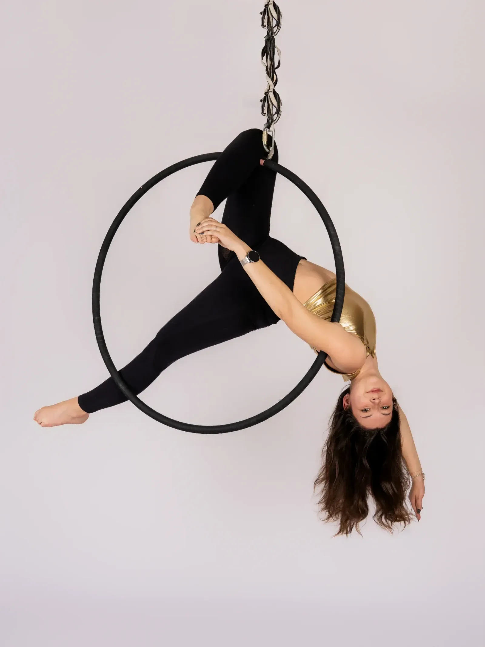 Aerial hoop – lektorka visí v kruhu hlavou dolů, má zaháknutou nohu a drží ji rukama ve studiu Prostě se hýbej, Opava.