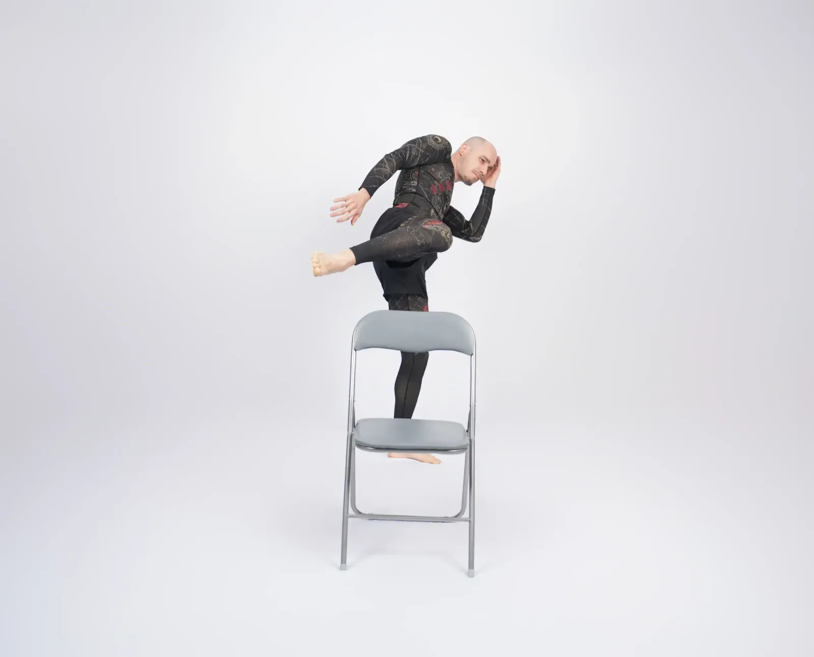 Chairdance – lektor balancuje na židli v dynamické pozici s nataženou nohou ve studiu Prostě se hýbej, Opava.